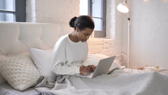 Young African Girl Celebrating Success on Laptop While Sitting in Bed