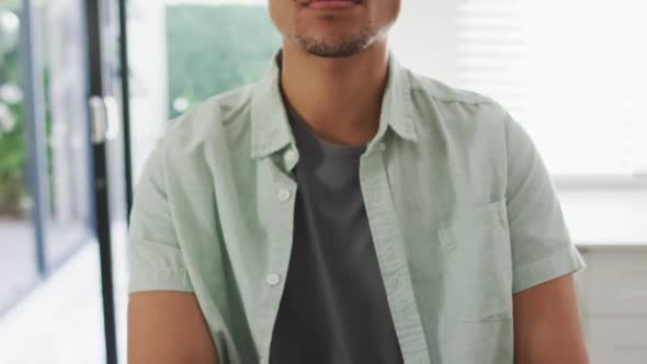 Happy biracial man sitting at table in kitchen reading braille