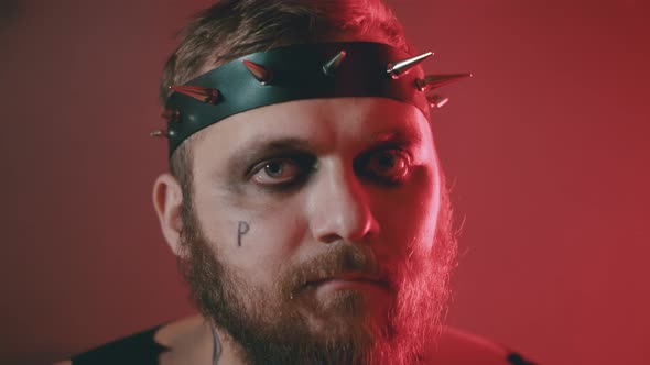 Close Up Portrait of Bearded Brutal Man Wearing Head Accessory with Thorns and Black Eyes Makeup