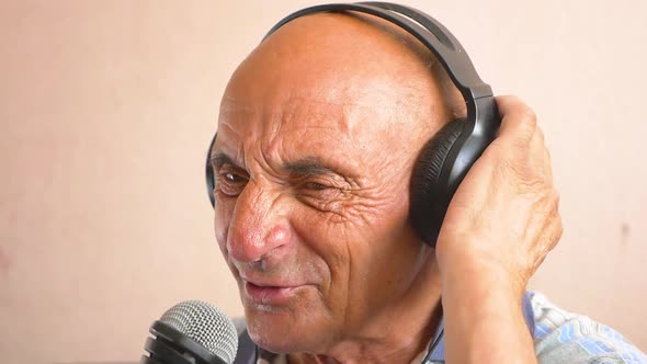 portrait of a pensioner singing into a microphone. An elderly cheerful Caucasian man in headphones s