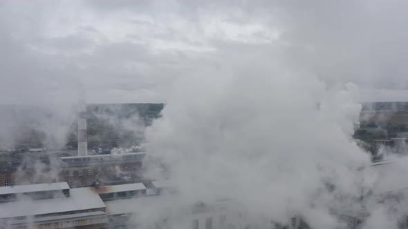 Aerial Footage on a Cloudy Day Through Smoke Coming Out of a Factory Chimney