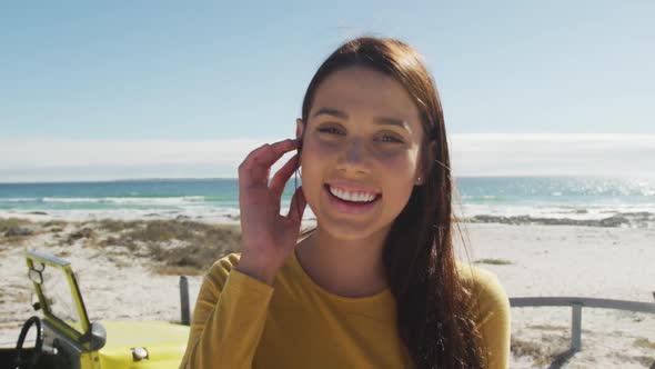 Happy caucasian woman standing near beach buggy by the sea