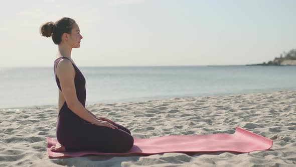Young Beautiful Woman Practicing Yoga on the Beach at Sunny Day