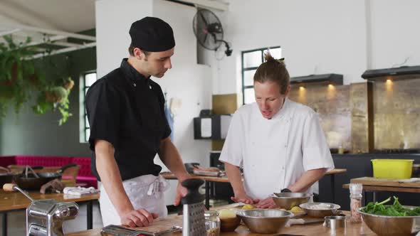 Caucasian female chef teaching diverse group preparing dishes and smiling