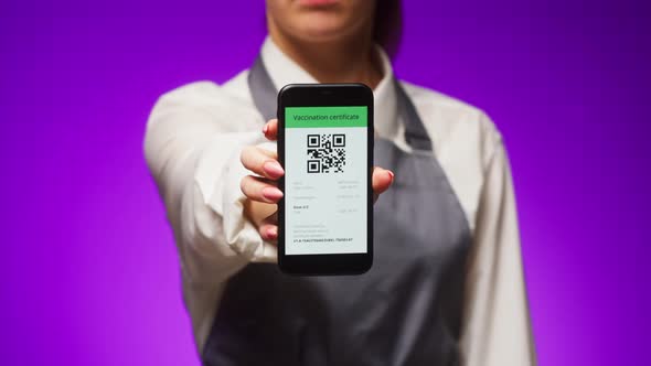 Woman Worker Showing on Phone Vaccination Passport with Qr Code on Purple Background International