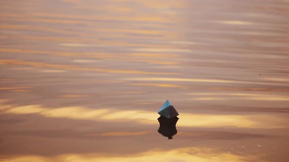 Paper boat on evening water.