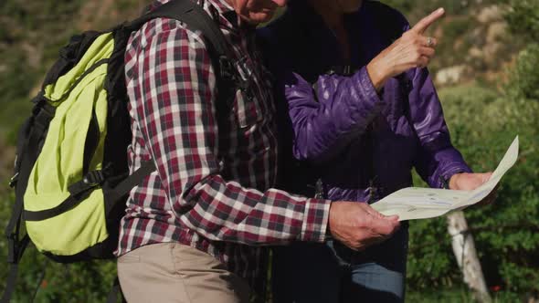 Active senior couple looking map on mountains