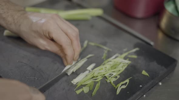 Closeup of Male Chef’s Hands Slicing Vegetables on Cutting Board