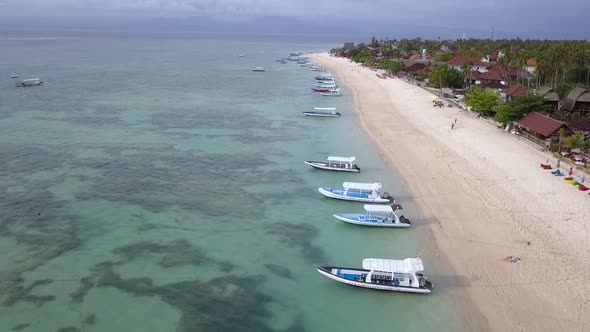 Flying over frothy waves of turquoise Indian Ocean to deserted beach with white sand surrounded by l