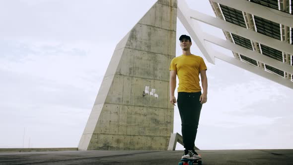 Young Attractive Trendy Man skateboarding fast under a solar panel on a morning sunny day with an ur