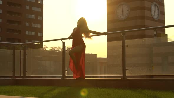 Beautiful Young Girl Dancing on the Street of a Modern City in the Sunset Light