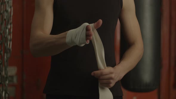 Fighter Wrapping Fists with Protective Tape in Gym