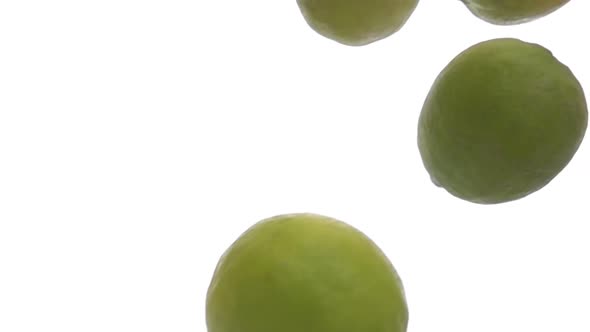 Closeup of the Fresh Limes Falling Down on the White Background