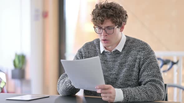 Young Young Man Reacting to Loss on Documents at Work