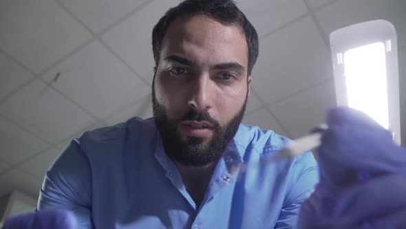 Patient Point of View of Handsome Middle Eastern Dentist Manipulating. Portrait of Serious Confident