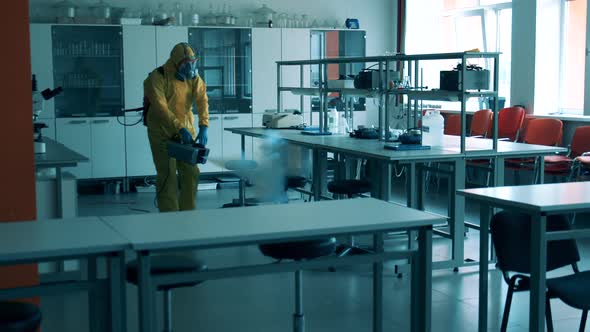 A Man in Protective Suit Disinfects a Class Room.