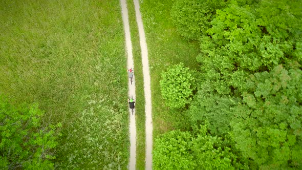 Aerial view of man and woman cycling on dirt road in the summertime.