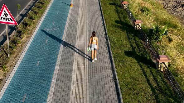 Fit girl walks along the embankment aerial view 4 K