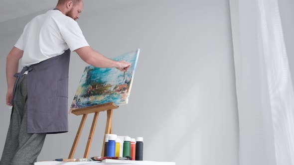 An Artist Working on Landscape Painting Uses a Brush to Create a Modern Painting