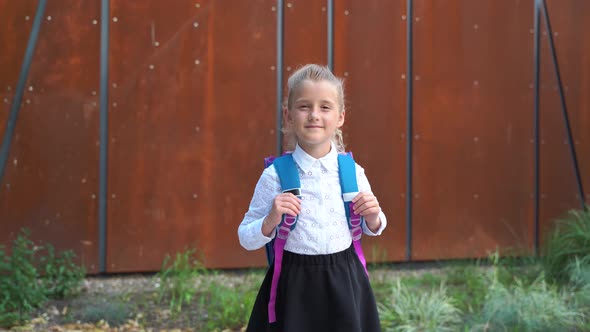 Smiling Little Girl with Modern Haircut in White Shirt with Rucksack