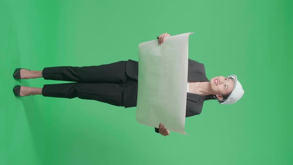 Full Body Of Asian Female Engineer Looking At Blueprint In The Green Screen Studio
