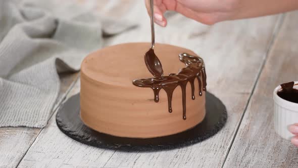 Glazing chocolate cake with melted chocolate. Woman pouring chocolate over cake.