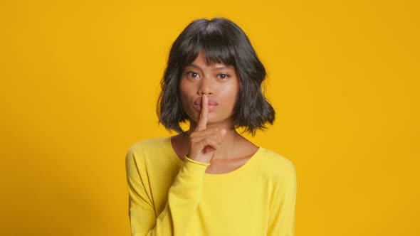 Mysterious Dark Skinned Woman Presses Index Finger To Lips Makes Silence Gesture