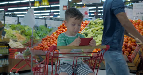 Mom with Children Make Purchases in Hyper Markite, the Child Sits in a Cart with Products 