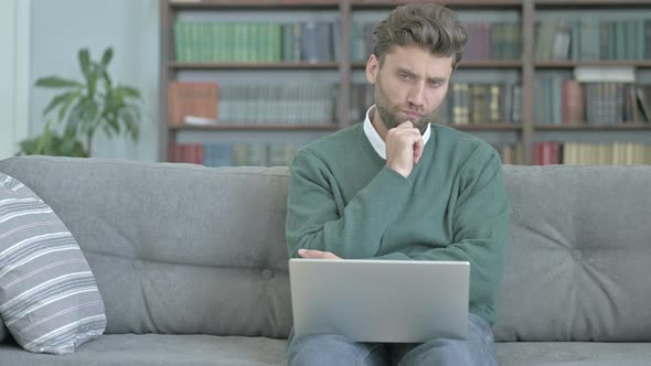 Thoughtful Man Contemplating While Working on Laptop