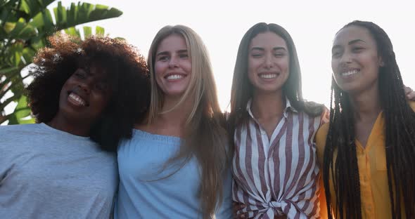 Young multiracial women hugging each other in the city with sunset in background