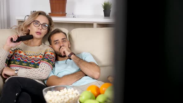 Revealing Shot Couple Sitting on the Couch Talking, Eating Popcorn and Watching TV