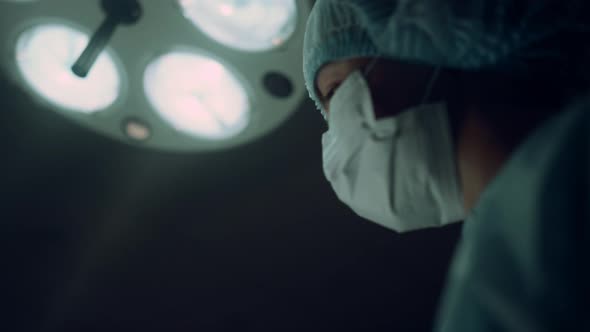 Portrait Nurse Performing Operation Holding Medical Clamp in Operating Room