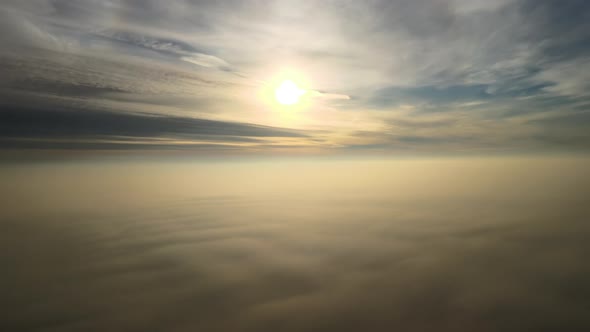 Aerial View of Vibrant Yellow Sunrise Over White Dense Clouds with Blue Sky Overhead