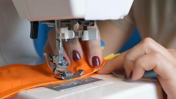 Seamstress Sews Fabric and Zippers with Machine at Workplace