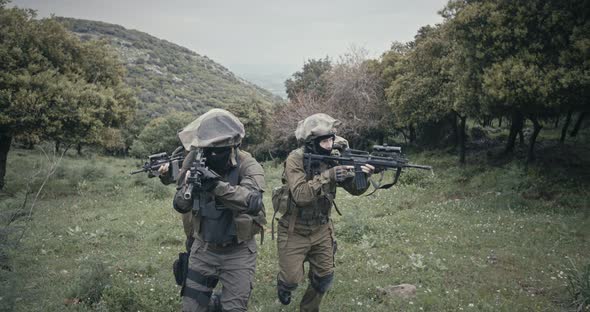 Squad of fully armed commando soldiers during combat in a forest scenery