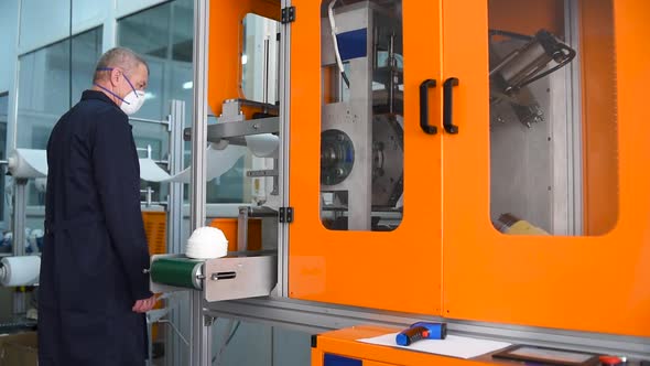 A man works at a machine for the manufacture of medical masks with nanofiber.