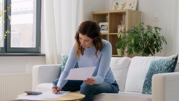 Woman with Papers and Calculator at Home