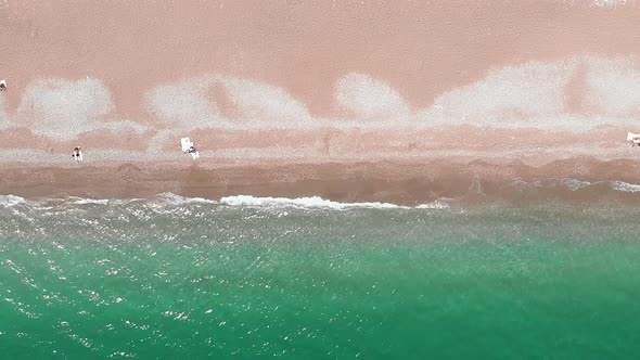 Clear turquoise sea waves breaking on sandy beach, splashing and creating white foam alt