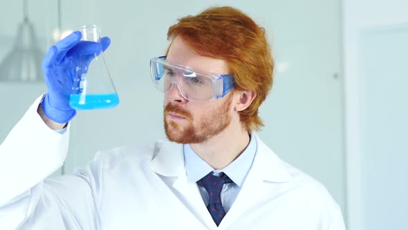 Scientist, Doctor Looking at Blue Solution in Flask in Laboratory alt