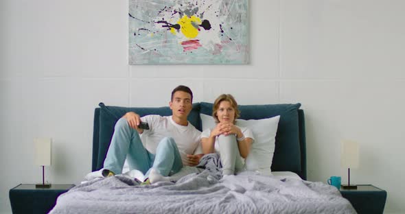 Young Mixed Couple Is Watching Football, Lying in Bed, Celebrating Scored Goal
