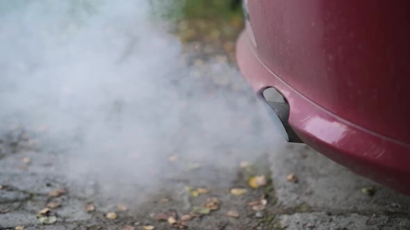 The exhaust pipe of a faulty car emits first light and then dark smoke