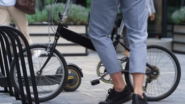 Man Getting Off Bicycle on Sidewalk at Downtown