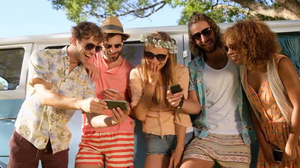 Hipster friends looking at smartphone and laughing