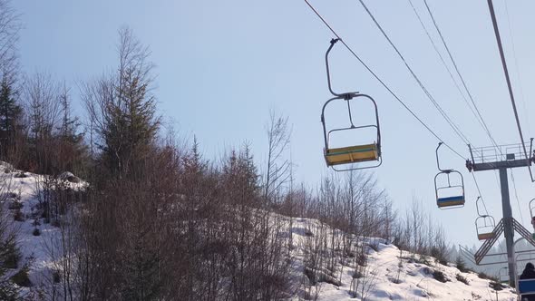 Ski Lift Carrying Skiers on Slope Against Blue Sky at Sunny Day in the Carpathians