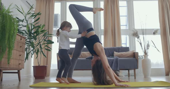 Young Beautiful Woman and Her Little Baby Girl Training Stretching at Home