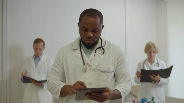 Handsome African American Male Physician with Tablet Pc in Lab Coat Smiling at Hospital