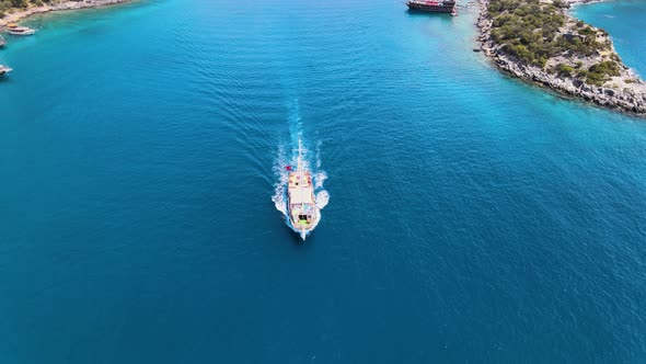 Drone fly over a bay in the Mediterranean over a yacht sailing between islands covered in green tree