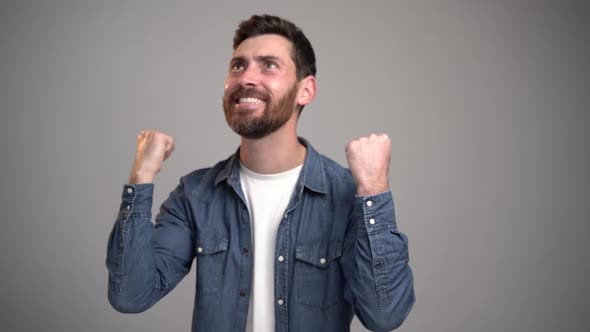 Portrait of ecstatic overjoyed handsome man expressing winning gesture with raised fists