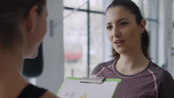 Close up of young woman talking with personal trainer at gym.  Shot with RED helium camera in 8K