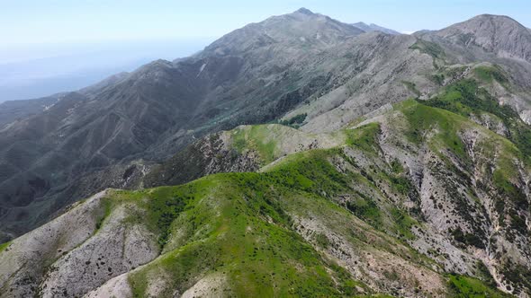 Drone aerial view of the top of a high mountain range with clear blue sky